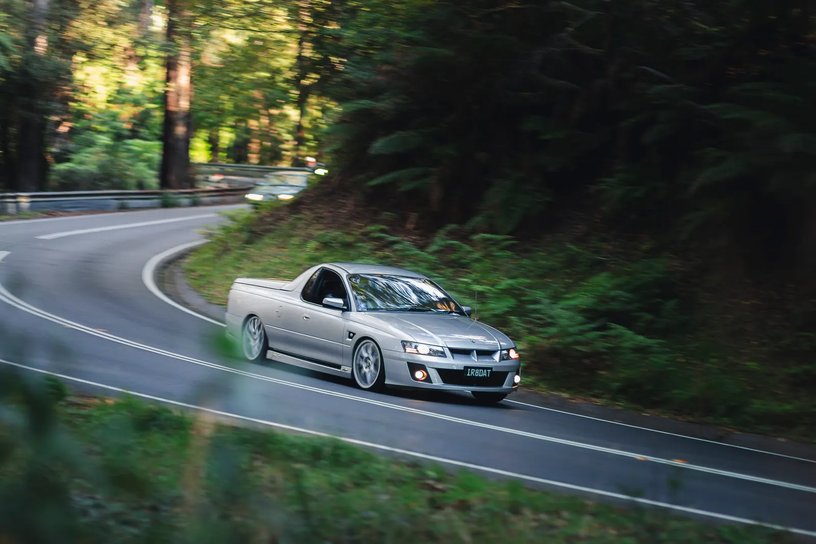 Silver sports utility vehicle navigating a curved mountain road through dense forest.
